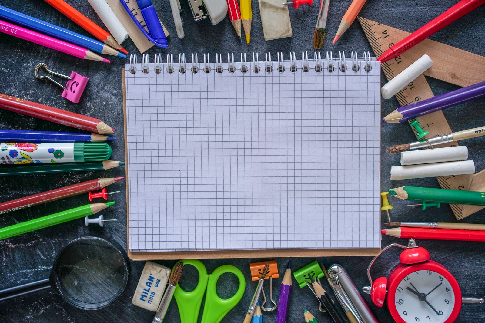 Colorful school and creative supplies arranged around a notebook